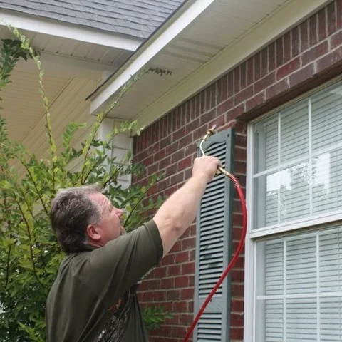David McNeece applying perimeter pest treatment around a Madison MS home's window and shutters